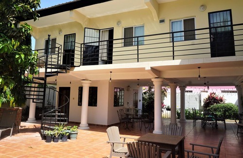 Serrekunda Cama Y Desayuno | Bonita habitación con cama doble junto a la piscina en un jardín tropical.