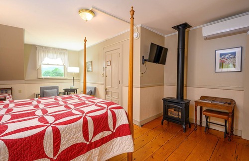 Stowe Cama Y Desayuno | Comfortable room with queen bed and daybed with windows on 3 sides, a stunning view of Mount Mansfield and a parlor stove with full service breakfast included
