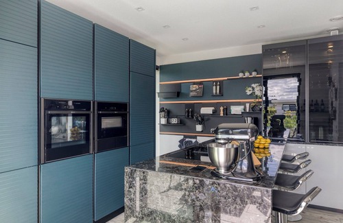 Zeewolde Casa | Detached 6-person villa by the water with a cosy living room featuring a piano and fireplace, modern kitchen with cooking island, and a sunny garden with lounge set.