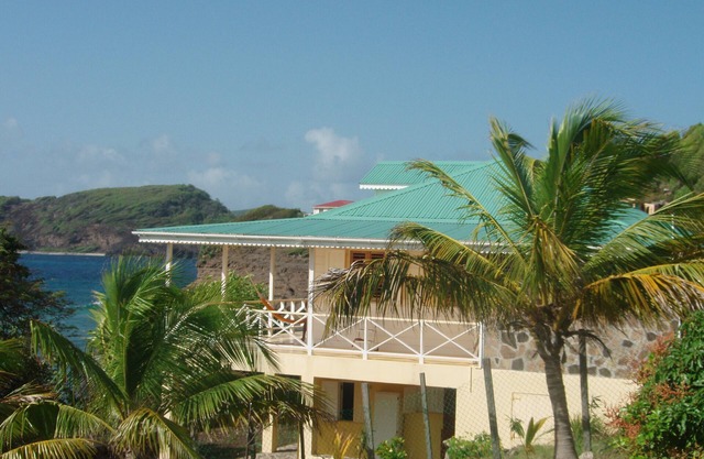 Encantadora villa del Caribe sobre el océano con porche y vistas al mar envolventes.