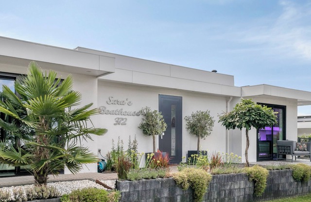 Detached 6-person villa by the water with a cosy living room featuring a piano and fireplace, modern kitchen with cooking island, and a sunny garden with lounge set.