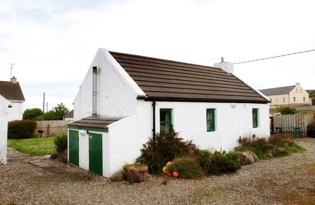 Tradicional y pequeña cabaña irlandesa encantadora con hermosas vistas al mar