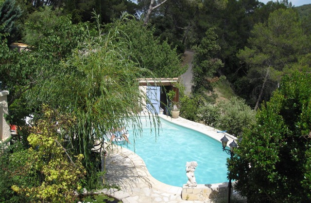 Casa de campo provenzal en piedras naturales en una colina boscosa con piscina.