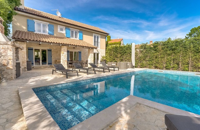Villa de lujo con piscina y barbacoa, rodeada de zonas verdes, mobiliario moderno