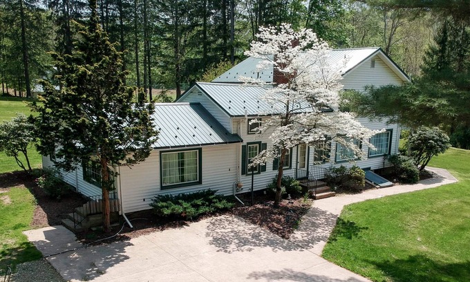 Hillsgrove Casa | Creek side house with fireplace and concrete driveway.