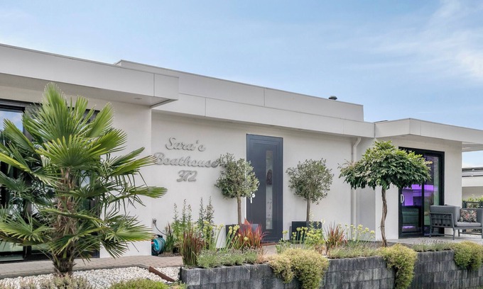 Zeewolde Casa | Detached 6-person villa by the water with a cosy living room featuring a piano and fireplace, modern kitchen with cooking island, and a sunny garden with lounge set.